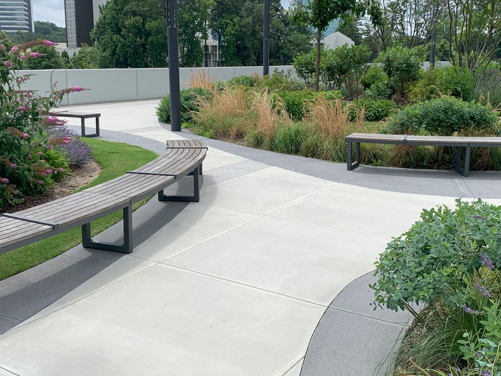 Backless Ogden Benches line pathway surrounded by greenery